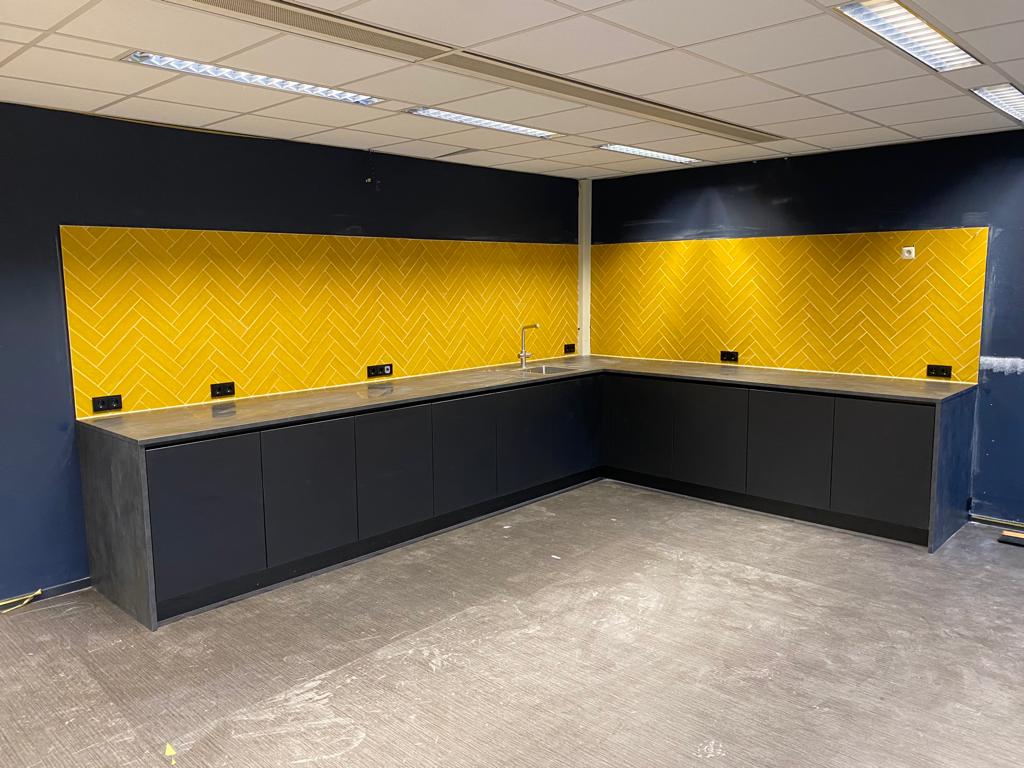 Mat/Glans Gele tegels boven de keuken in visgraatmotief @Weustman Harderwijk